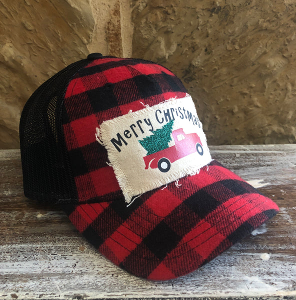 Red and black checkered cap with 'Merry Christmas' patch on a wooden surface
