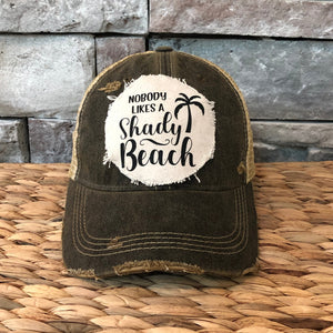Vintage-style cap with 'Nobody Likes a Shady Beach' text on a stone wall background