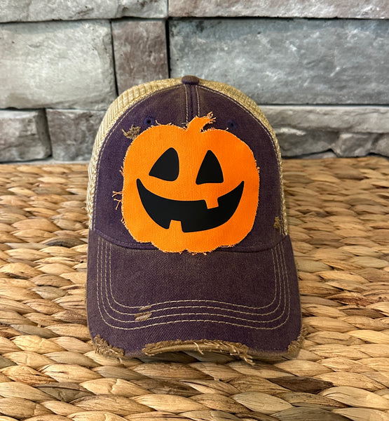 Trucker hat with a pumpkin face design on a woven surface with stone wall background